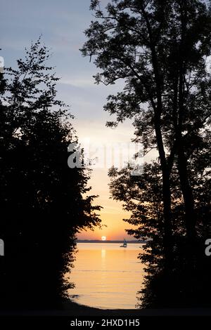 Barca a vela al tramonto sul lago Chiemsee in Baviera, Germania Foto Stock