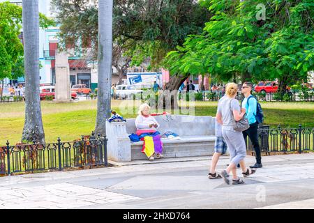 Persone in una piazza e donna cubana che legge la carta dei tarocchi in panchina, l'Avana, Cuba, marzo 2017 Foto Stock