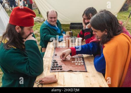 Inghilterra, East Sussex, Battle, The Annual Battle of Hastings 1066 Re-enactment Festival, partecipanti vestiti in costume medievale giocando Backgammon Foto Stock