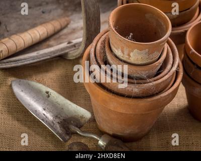 Pentole in terracotta ricoperte di Cobweb con cazzuola e tradizionale abbraccio in legno sullo sfondo. Foto Stock