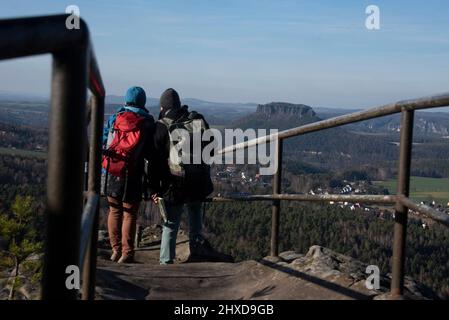 Due escursionisti sul Papststein, dietro di loro il Lilienstein, montagna da tavola in Elbsandsteingebirge, situato in Malerweg, Pastdorf, Sassonia, Germania Foto Stock