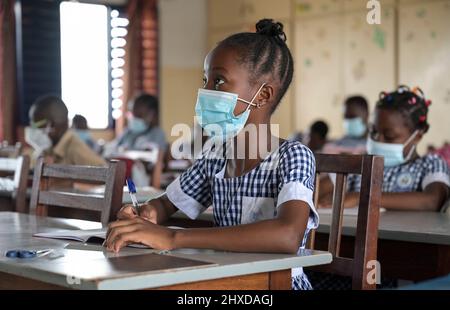 COSTA D'AVORIO, Abidjan, Scuola cattolica, Corona Times, allievo con maschera facciale / ELFENBEINKUESTE, Abidjan, Stadtteil Koumassi-Remblais, Foyer Marie Dominique von den Soeurs Salesiennes de Don Bosco / Filles Marie Auxiliatrice (FMA), Schule für Kinder in der Corona it mit Zeeken Foto Stock