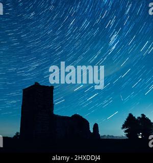 un meteor e sentieri stellari nel cielo notturno sopra Knowlton Church, Cranborne, Dorset, Inghilterra, Regno Unito, Durante le docce Perseid Meteor annuali (agosto 2021) Foto Stock