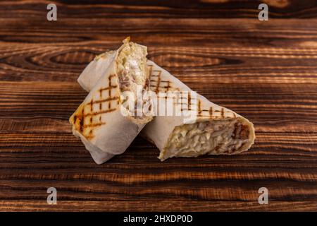 Sandwich arrotolato Shawarma con salsa e verdure, cibo tradizionale arabo. Shawarma Doner kebab wrap con pollo, patatine fritte e sottaceti. La Tradiitio israeliana Foto Stock