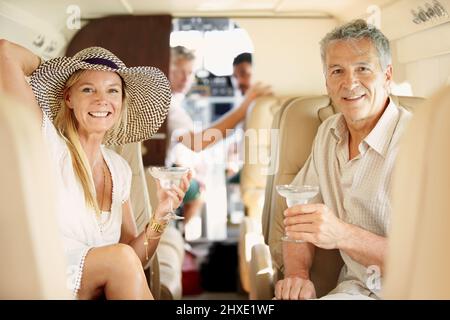 Volare con stile. Shot di una coppia matura seduta sul retro di un jet cocktail privato. Foto Stock