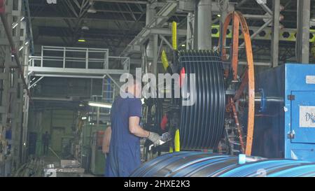 RUSSIA, ANGARSK - Giugno 8, 2018: bobina bobina di filettatura tubo. Fabbricazione di plastica tubazioni di acqua alla fabbrica. Processo per la fabbricazione di tubi in materiale plastico in ma Foto Stock