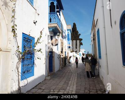 Tunisi. 12th Mar 2022. I turisti camminano su una strada nell'attrazione turistica di Sidi Bou Said a Tunisi, Tunisia, 11 marzo 2022. La Tunisia ha attenuato le restrizioni sanitarie sui turisti in arrivo dal marzo 1 e il numero di turisti nelle principali attrazioni è aumentato. Credit: Xinhua/Alamy Live News Foto Stock