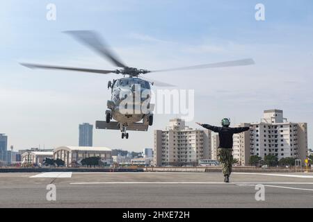 YOKOSUKA, Giappone (10 marzo 2022) Aviation Electronics Technician 3rd Class Bradley Douglas, di Latrobe, Pennsylvania, segnala un MH-60R Seahawk, attaccato ai “Saberhawks” di Helicopter Maritime Strike Squadron (HSM) 77, per atterrare al comandante, Fleet Activities Yokosuka. HSM-77 è collegato a Commander, Task Force 70 e Forward-schierato per l'area della flotta USA 7th di operazioni a sostegno di un libero e aperto Indo-Pacific. (STATI UNITI Foto Navy di Mass Communication Specialist 2nd Classe Erica Bechard) Foto Stock