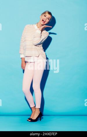 Mostrando la sua risorsa più grande. Una bella giovane donna in elegante abbigliamento retrò sorridente con la palma tenuta aperta sotto il viso. Foto Stock