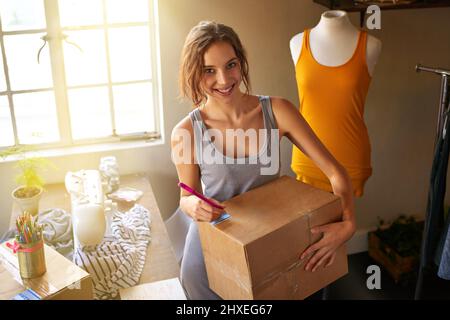 La moda riguarda la suspense, la sorpresa e la fantasia. Scatto di un progettista che prepara i suoi progetti per la consegna. Foto Stock