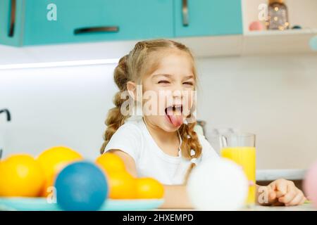 Una bambina di 7-8 anni distorce il viso dopo aver bevuto succo d'arancia appena spremuto. Emozioni del bambino Foto Stock