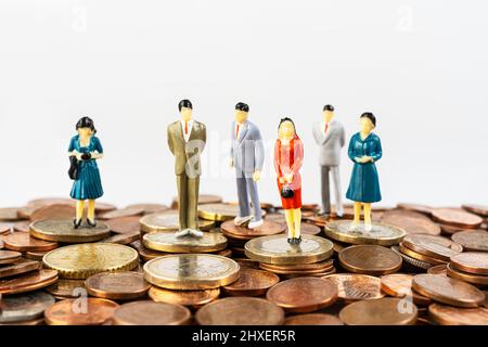 alcuni modelli in miniatura su una superficie ricoperta di monete in euro Foto Stock