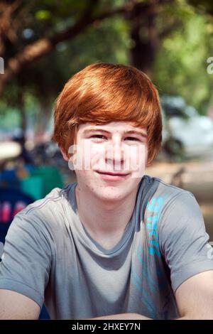 Ragazzo con i capelli rossi e piccone in faccia sembra felice Foto Stock