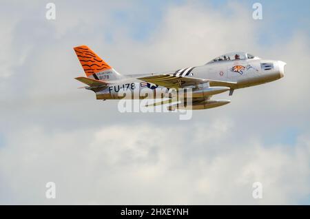 F-86A nordamericano Sabre jet plane vintage. United States Air Force 1950s classico caccia jet in Tiger schema volare a un airshow. G-SABR Foto Stock