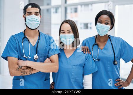 Il nostro obiettivo è quello di ottenere una salute ottimale. Ritratto di un gruppo di medici che indossano maschere per il viso in un ospedale. Foto Stock