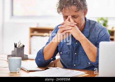 Im diventare troppo vecchio per questo.... Scatto di un uomo d'affari maturo che guarda stanco mentre lavora alla sua scrivania d'ufficio. Foto Stock