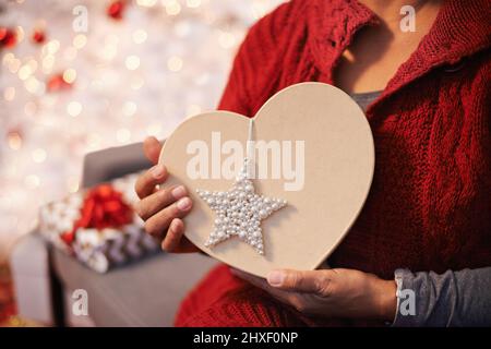 Il palato ha avuto un cuore per natale. Vista ritagliata di una donna che tiene un cuore plasmato regalo di Natale. Foto Stock