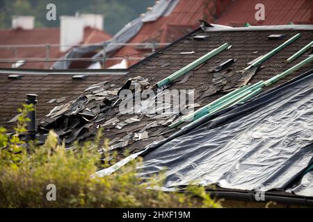 Tetto danneggiato da tempesta, tegole distrutte, danni costosi che richiedono una riparazione immediata Foto Stock