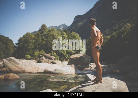 Acque turchesi del fiume Verzasca vicino a Lavertezzo, Ticino, Svizzera - giovane che va per una nuotata Foto Stock