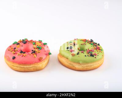 Ciambella rosa e verde assortita con spolverino colorato isolato su sfondo bianco, spazio di copia per il testo Foto Stock