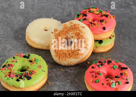 Ciambella assortita con spruzzatura colorata isolata su cemento grigio sfondo, Copia spazio per testo Foto Stock