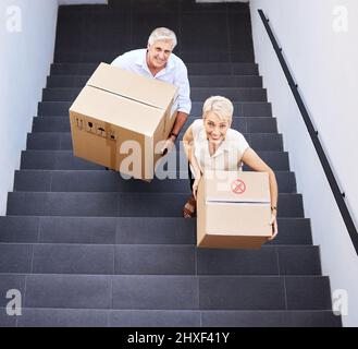 Fai il passo per ricordi nuovi di zecca. Scatto di una coppia matura che porta le scatole sulle scale in un giorno in movimento. Foto Stock