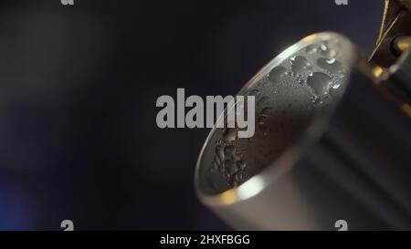 Primo piano del beccuccio del bollitore in acciaio con gocce d'acqua sulla superficie. Azione. Vapore proveniente dal beccuccio del bollitore su sfondo sfocato. Foto Stock