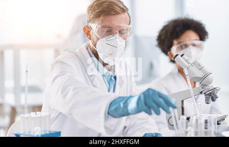 scienziato in abbigliamento protettivo che esamina i campioni in laboratorio. Foto Stock