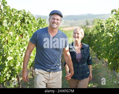 Camminando attraverso le viti insieme. Una coppia matura di soddisfare passeggiando attraverso un vigneto insieme. Foto Stock