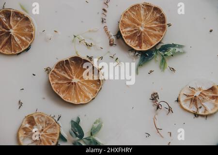 Primo piano di un bagno terapeutico al latte pieno di fette di limone e altre erbe aromatiche per il benessere, la bellezza e il benessere Foto Stock