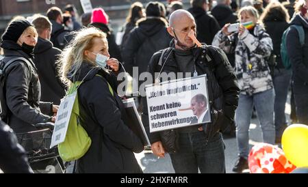 12 marzo 2022, Amburgo: Un dimostratore con un naso Pinocchio porta un segno che recita: 'Nessuna vaccinazione obbligatoria. Non conosce effetti collaterali gravi". I critici delle imponenti misure sanitarie stanno dimostrando qui sotto lo slogan "contro le maschere obbligatorie e altre misure di contenimento di Corona". Foto: Markus Scholz/dpa Foto Stock