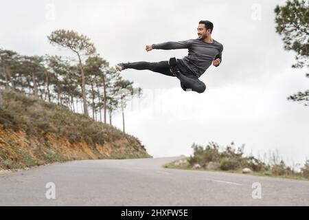 Il mio corpo è costruito per superare gli ostacoli. Scatto a tutta lunghezza di un bel giovane uomo che fa un calcio volante durante il suo allenamento all'aperto. Foto Stock