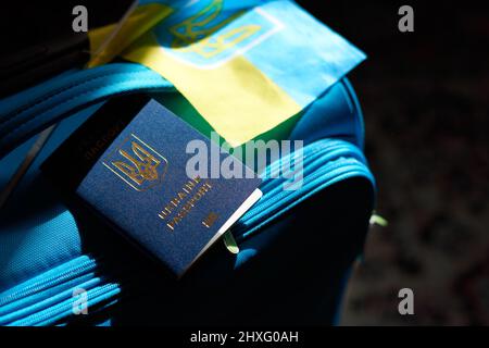 Bagaglio per rifugiati ucraini con passaporto e bandiera giallo-blu. Evacuazione di civili, famiglie dall'Ucraina che attraversano la frontiera. Arrestare la guerra, supportare U. Foto Stock