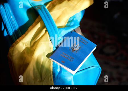 Bagaglio per rifugiati ucraini con passaporto e bandiera giallo-blu. Evacuazione di civili, famiglie dall'Ucraina che attraversano la frontiera. Arrestare la guerra, supportare U. Foto Stock