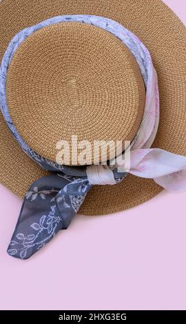 Cappello di paglia femminile con arredamento in tessuto vista dall'alto su rosa chiaro con spazio copia. Concetto di viaggio estivo Foto Stock