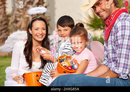 Trick-o-trattando come una famiglia. Il colpo corto di una famiglia fuori il theyve di ossequi raccolto su Halloween. Foto Stock