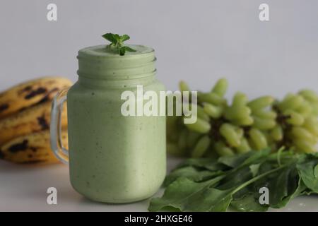 Frullato verde a base di uva verde congelata, spinaci freschi, banane e latte di mandorle. Servito in vasetto di mason. Scatto su sfondo bianco. Foto Stock