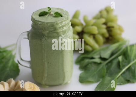 Frullato verde a base di uva verde congelata, spinaci freschi, banane e latte di mandorle. Servito in vasetto di mason. Scatto su sfondo bianco. Foto Stock