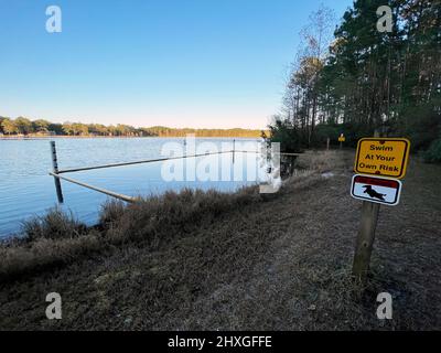 A causa della presenza di alligatori, un cartello per nuotare a proprio rischio è apparsi su un lago della Georgia. Foto Stock