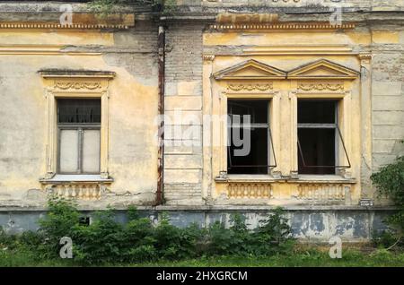 Tre finestre sulla facciata rovinata di una vecchia casa abbandonata a mol, Backa, Serbia Foto Stock