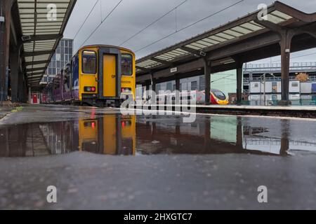 Northern Rail classe 150 treno sprinter nella baia sud alla stazione ferroviaria di Preston riflesso in un pozzanghere con un treno Virgin treni Alstom Pendolino Foto Stock