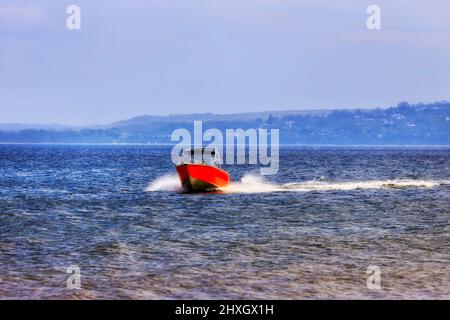 Piccola barca a motore sulla superficie delle acque della baia di Jervis al largo della spiaggia di Callala in una giornata estiva soleggiata. Foto Stock