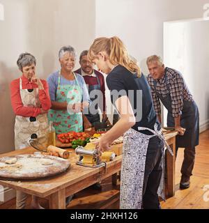 Niente riunisce le persone come un buon cibo. Shot di un gruppo di anziani che frequentano una lezione di cucina. Foto Stock