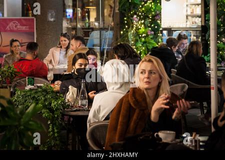 Immagine di una giovane donna caucasica bianca cliente di un caffè ristorante sulla terrazza a belgrado, serbia, che indossa una maschera respiratoria durante il coro Foto Stock