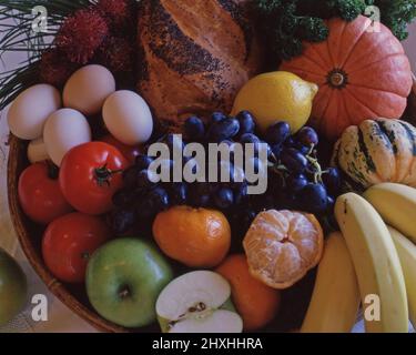 CESTINO DI FRUTTA MISTA FRESCA (LIMONE, UVE, BANANE, MELE E MANDARINI) PANE DI PANE SEMINATO, ZUCCHINE E UOVA. Foto Stock