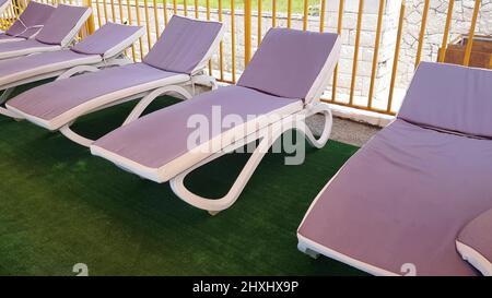 sedie a sdraio vuote si trovano in fila sotto il tetto del solarium per prendere i bagni d'aria sulla riva del mare, una località turistica Foto Stock