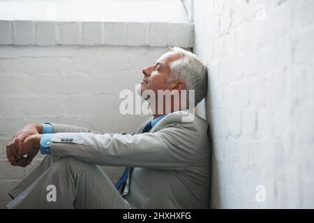 Mantenere un momento a se stesso. Un uomo d'affari rilassato seduto a terra. Foto Stock