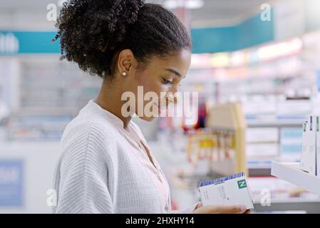 Scegliere sempre saggiamente quando si tratta di salute. Primo piano di una giovane donna attraente che legge attraverso il contenuto di un prodotto in una farmacia. Foto Stock