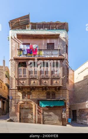 Finestra in stile oriel dell'era Mamluk con griglia di legno intercalata - Mashrabiya, su muro esterno in shabby, in 1890 edificio residenziale storico conosciuto come casa di Sokkar, distretto di Bab al Wazir, vecchio Cairo, Egitto Foto Stock