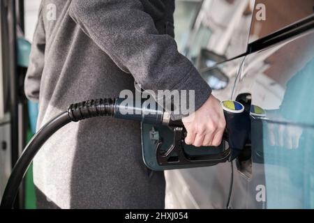 Uomo irriconoscibile che riempie il suo serbatoio del veicolo con diesel in una stazione di servizio. Foto Stock